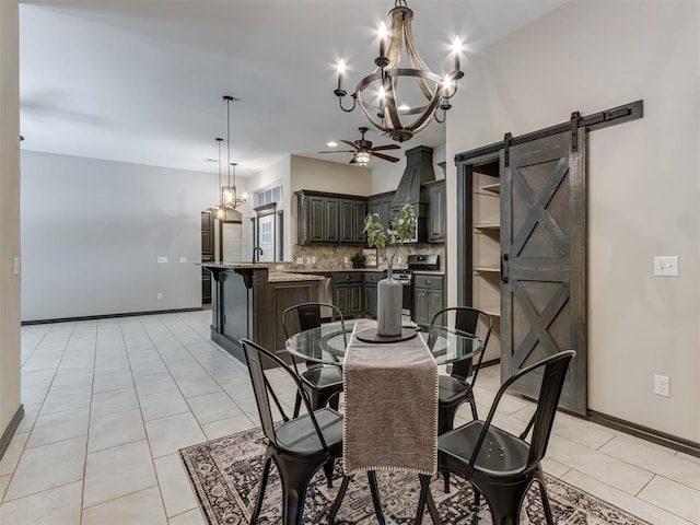 dining area featuring a barn door, light tile patterned floors, ceiling fan with notable chandelier, and baseboards