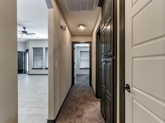 corridor with visible vents, light colored carpet, and baseboards