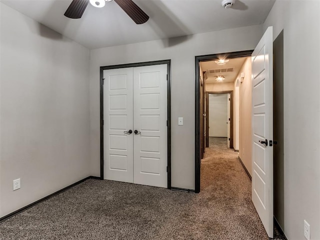 unfurnished bedroom with dark colored carpet, a closet, baseboards, and visible vents