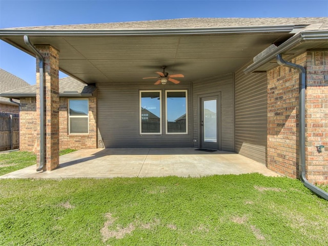 exterior space with a patio area, a lawn, brick siding, and ceiling fan