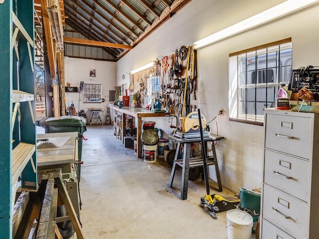 miscellaneous room featuring a workshop area, concrete floors, and high vaulted ceiling