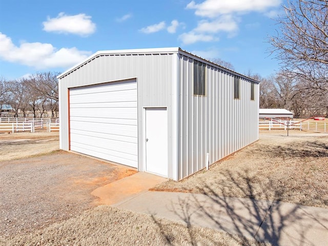 detached garage featuring fence and driveway