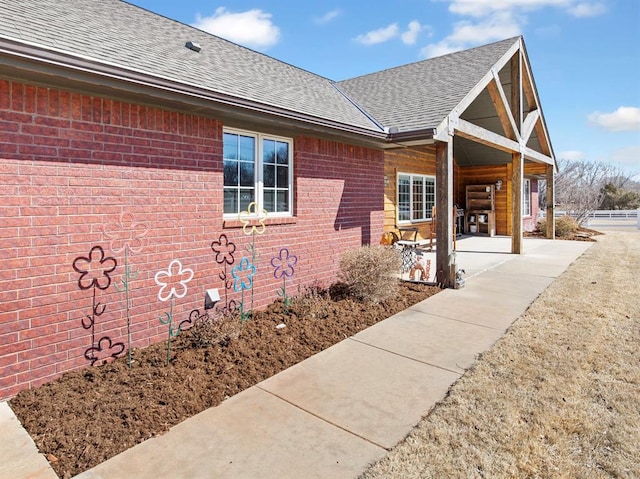 view of side of home featuring brick siding and a shingled roof