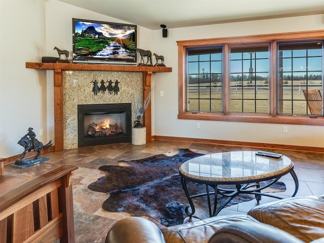 living room featuring stone finish floor, a fireplace, and baseboards