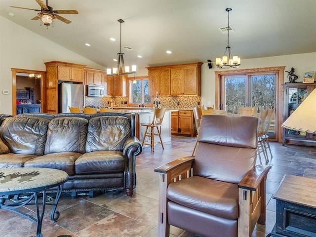 living area with stone tile floors, visible vents, high vaulted ceiling, recessed lighting, and ceiling fan with notable chandelier