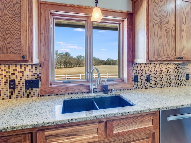 kitchen featuring brown cabinetry, dishwasher, tasteful backsplash, and a sink