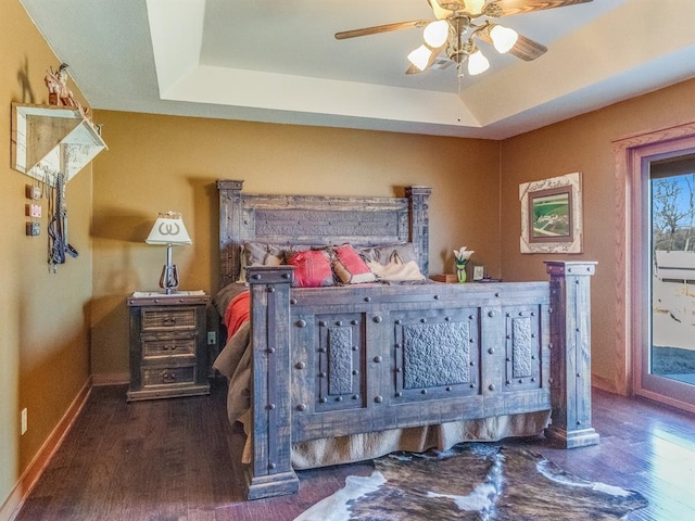 bedroom featuring wood finished floors, baseboards, a tray ceiling, ceiling fan, and access to exterior