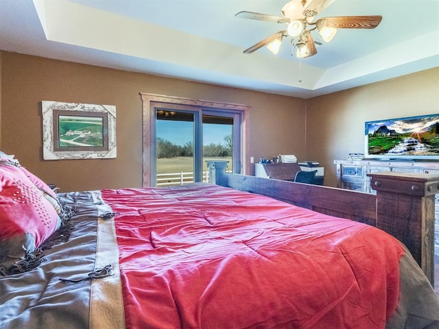 bedroom featuring a tray ceiling, access to exterior, and a ceiling fan