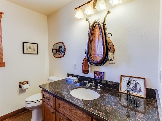 half bath featuring vanity, toilet, and wood finished floors