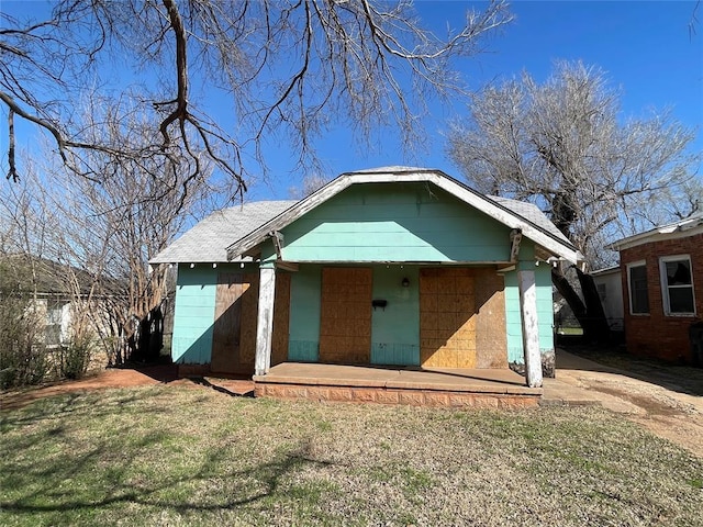 view of front of house with an outbuilding, concrete block siding, and a front yard