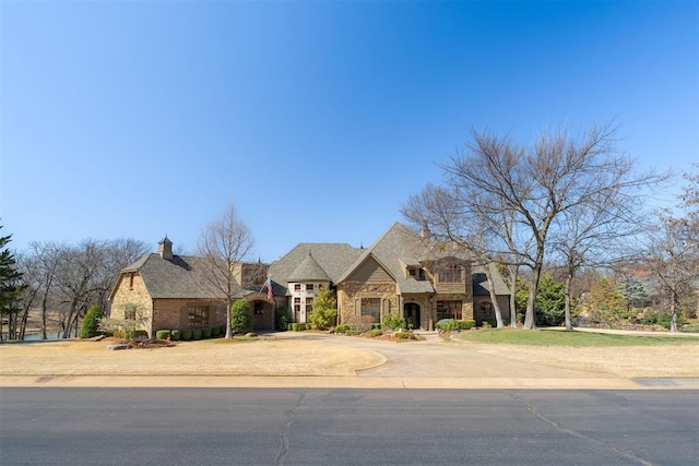 french country style house featuring stone siding and driveway