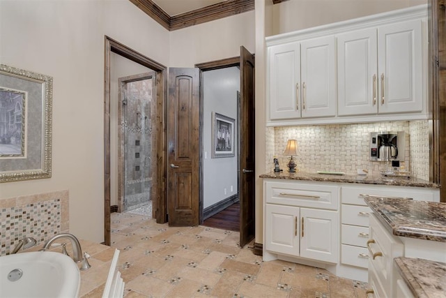 kitchen with backsplash, white cabinets, stone countertops, and crown molding