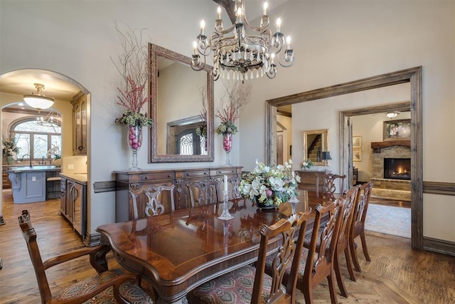 dining space featuring parquet flooring, a fireplace, and arched walkways