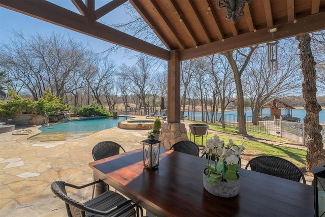 view of patio / terrace with a water view, outdoor dining space, fence, a fenced in pool, and an in ground hot tub