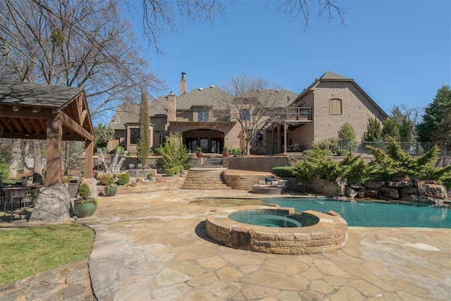 exterior space with a pool with connected hot tub, a patio, and fence