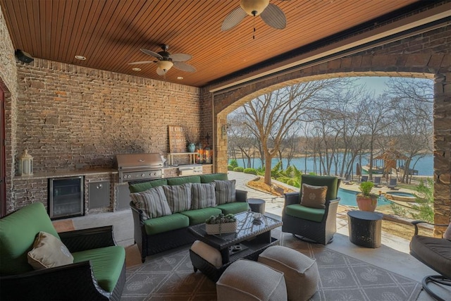 view of patio with exterior kitchen, area for grilling, wine cooler, a water view, and an outdoor hangout area