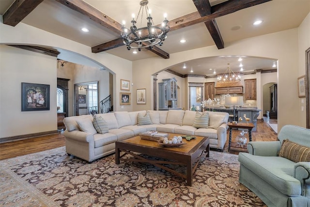 living area with wood finished floors, an inviting chandelier, beam ceiling, recessed lighting, and arched walkways