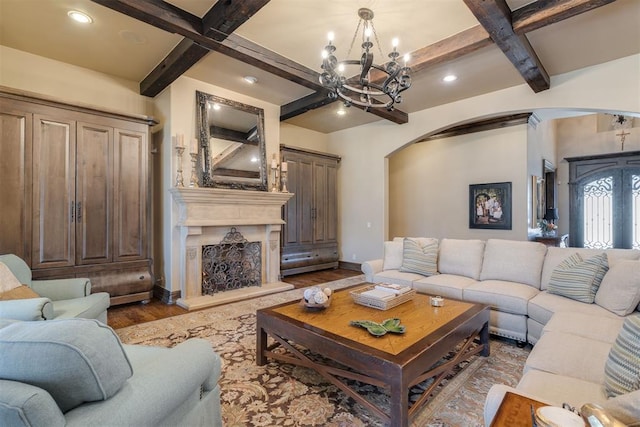 living area featuring baseboards, arched walkways, coffered ceiling, and wood finished floors