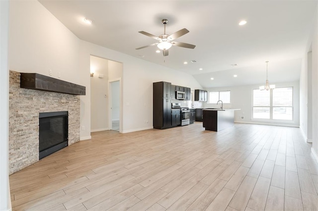 unfurnished living room featuring a glass covered fireplace, vaulted ceiling, light wood-type flooring, and ceiling fan