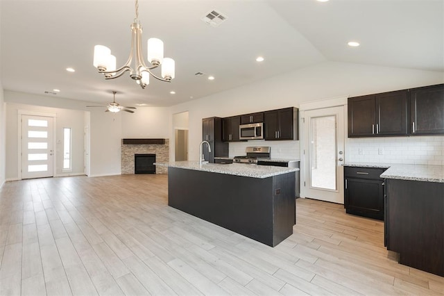 kitchen with a stone fireplace, visible vents, appliances with stainless steel finishes, and decorative backsplash