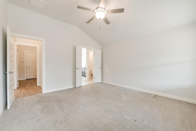 unfurnished bedroom featuring visible vents, ensuite bathroom, carpet, baseboards, and vaulted ceiling