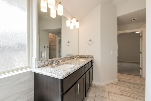 bathroom featuring double vanity, baseboards, visible vents, and a sink