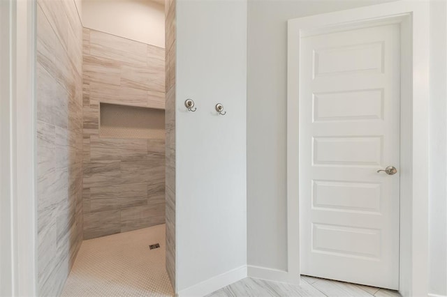 bathroom featuring baseboards and a tile shower