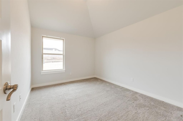 carpeted spare room with lofted ceiling and baseboards