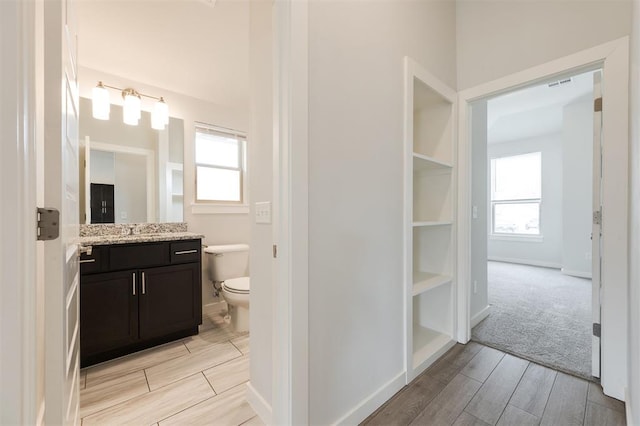 bathroom featuring baseboards, vanity, toilet, and wood tiled floor