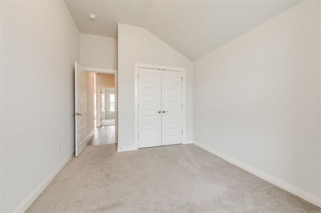 unfurnished bedroom with a closet, baseboards, carpet, and vaulted ceiling