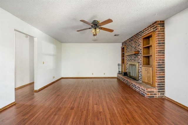 unfurnished living room with a textured ceiling, a brick fireplace, and wood finished floors