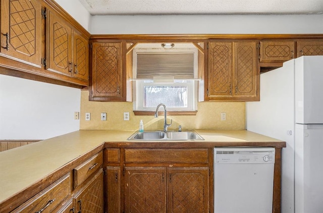 kitchen with brown cabinetry, dishwasher, light countertops, and a sink