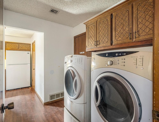 laundry room featuring visible vents, cabinet space, independent washer and dryer, and wood finished floors