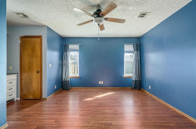 empty room featuring visible vents, baseboards, and wood finished floors