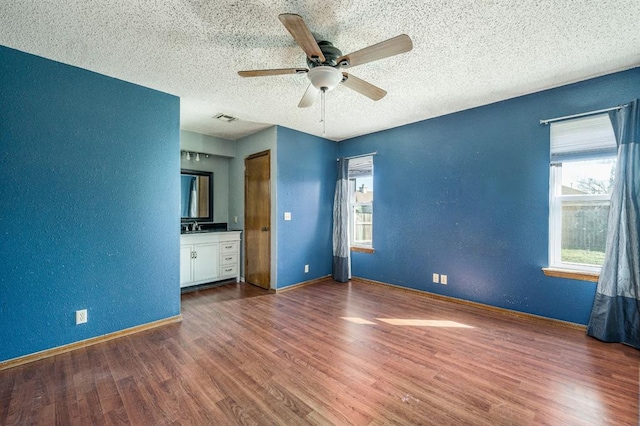 unfurnished bedroom featuring visible vents, a textured ceiling, a textured wall, and wood finished floors