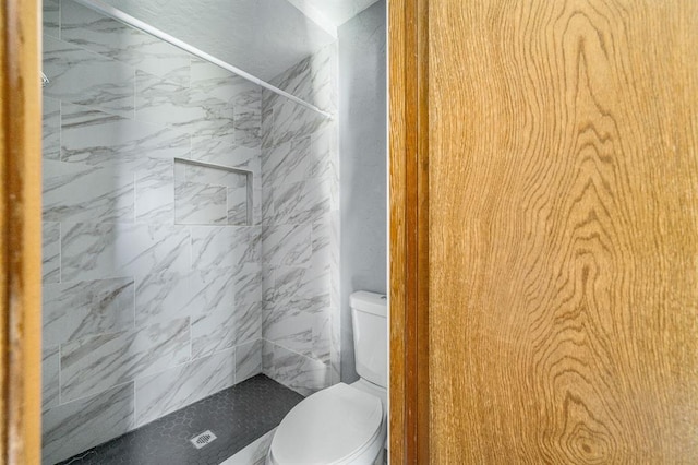 bathroom with toilet and a tile shower