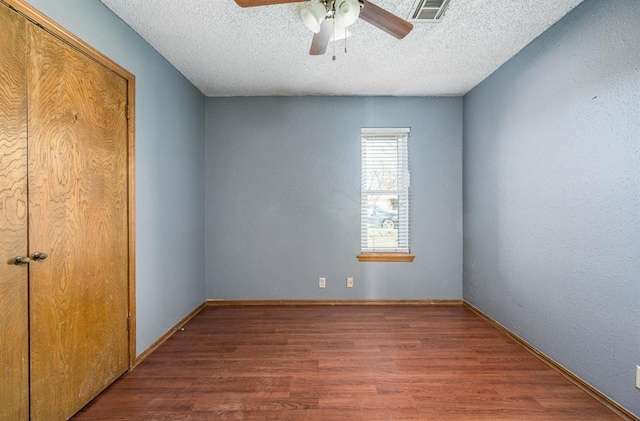 unfurnished bedroom featuring visible vents, baseboards, wood finished floors, a textured ceiling, and a ceiling fan