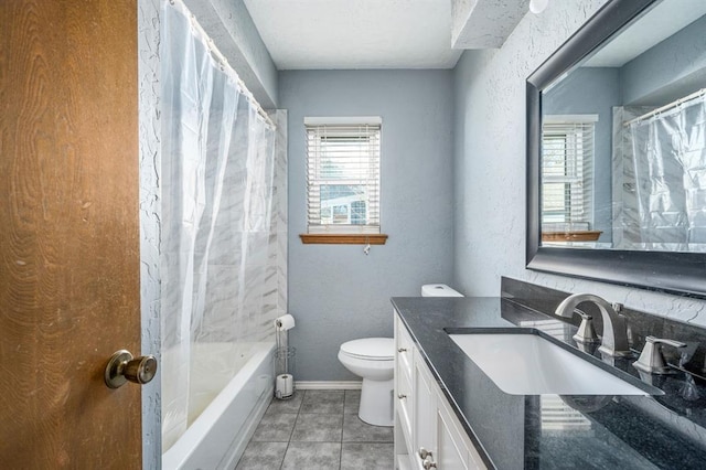 bathroom featuring tile patterned floors, toilet, baseboards, vanity, and a textured wall