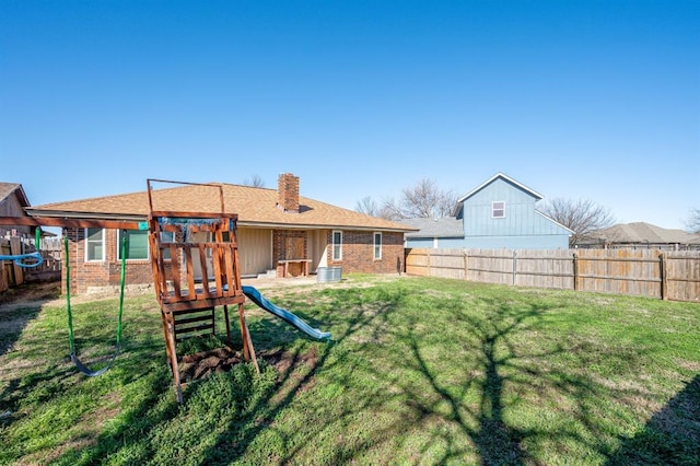 back of house with a yard, a fenced backyard, a chimney, and a playground