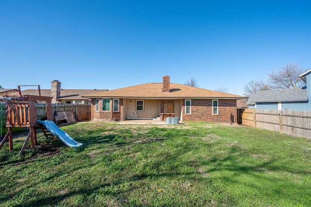 back of house with a yard, a fenced backyard, and brick siding