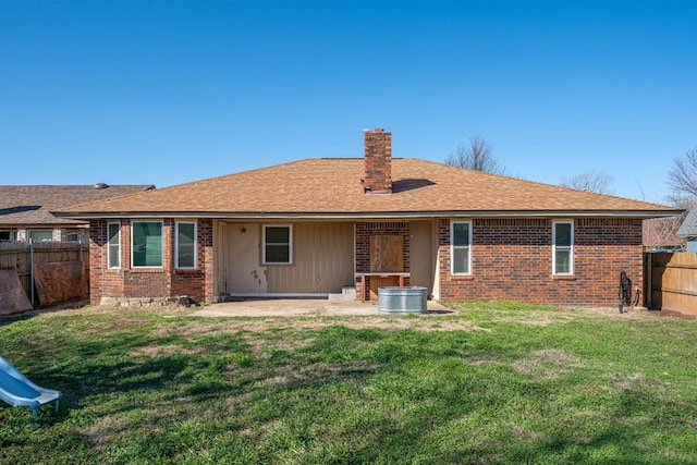 rear view of house with a fenced backyard, a yard, brick siding, a chimney, and a patio area