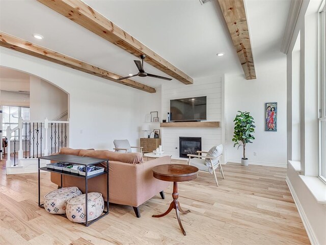 114 Alamosa Rd, Norman, OK 73069 - living room with a fireplace, beam ceiling, wood finished floors, ceiling fan, and arched walkways