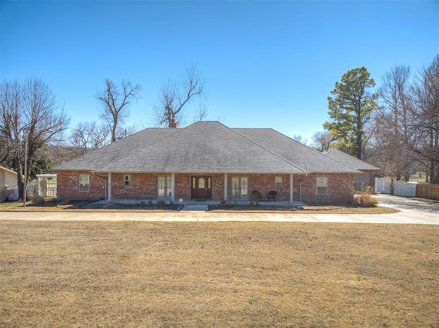 view of front facade featuring brick siding, a front lawn, and fence