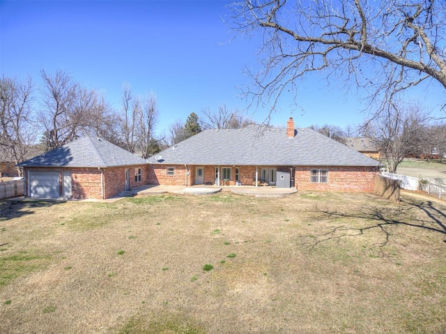 rear view of house with a lawn, fence, brick siding, a chimney, and a patio area