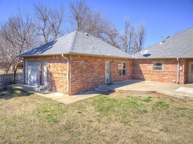 rear view of property featuring a patio, fence, a yard, an attached garage, and brick siding