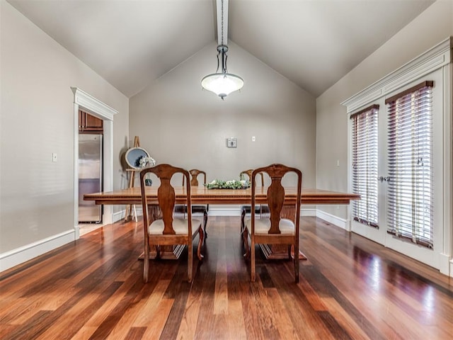 dining space featuring baseboards, wood finished floors, and vaulted ceiling with beams