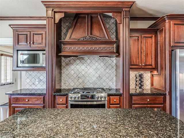 kitchen featuring backsplash, dark stone counters, stainless steel appliances, and custom range hood