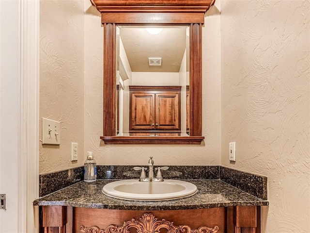 bathroom featuring vanity and a textured wall