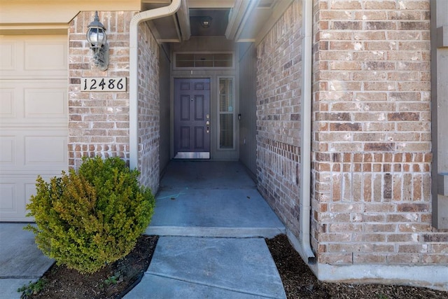 doorway to property featuring brick siding and an attached garage