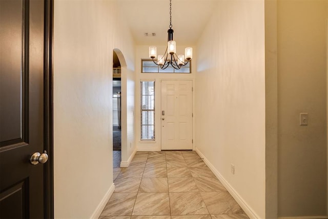 entrance foyer with visible vents, baseboards, arched walkways, and an inviting chandelier